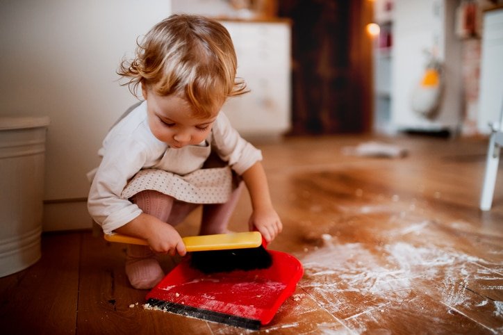 A parent and child happily organizing toys in a modern, clean home playroom.