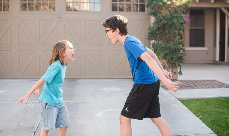 A parent observes two siblings who are upset and turned away from each other.