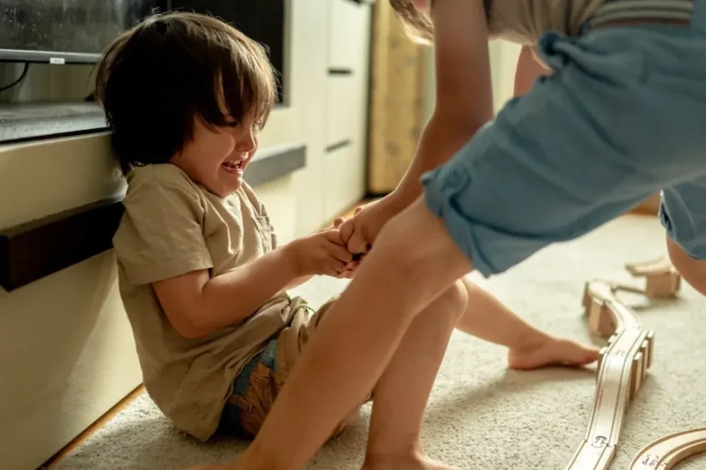 A sand timer sits on a table to regulate turn-taking between two young siblings.