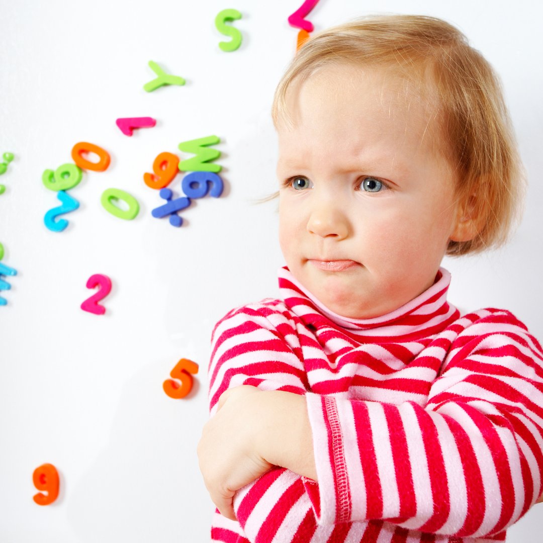 A toddler testing boundaries by reaching for an object in a living room.
