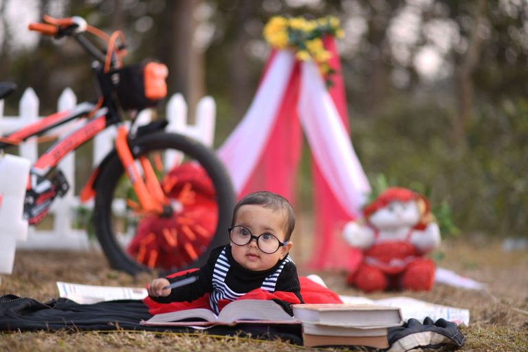 কোমল গালিচায় বসে রঙিন ছবির বই পড়ছে একটি ছোট্ট শিশু।